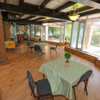 Spacious cafe interior with wooden flooring, large windows, and neatly arranged tables and chairs.