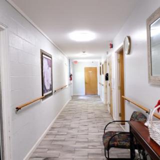 A clean and well-lit hallway in a healthcare facility with artwork on the walls and handrails for support.