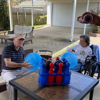 Two elderly individuals engaging in a fun outdoor activity with balloons and colorful toys.
