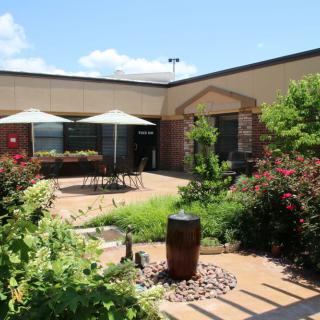 A well-landscaped courtyard featuring outdoor seating with umbrellas on a sunny day.