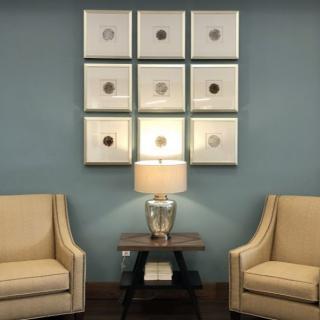 A cozy living room setup with two beige armchairs flanking a side table and lamp, complemented by modern wall art.