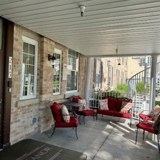 A cozy and inviting porch featuring red outdoor seating and a view of greenery.