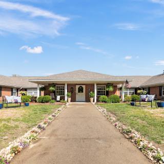 A welcoming residential building surrounded by well-maintained landscaping and a clear blue sky.