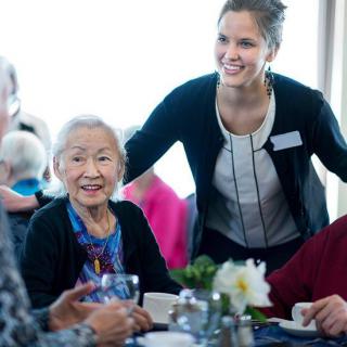 A caregiver interacts warmly with seniors at a group gathering.