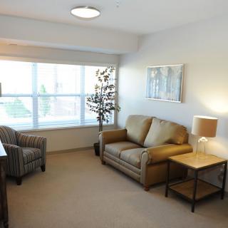 A cozy living room with a sofa, armchair, and soft lighting.