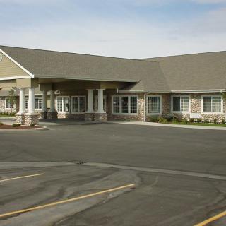 A single-story facility with a large parking area in front.
