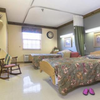 A shared hospital room with two patient beds, a rocking chair, and personal items.
