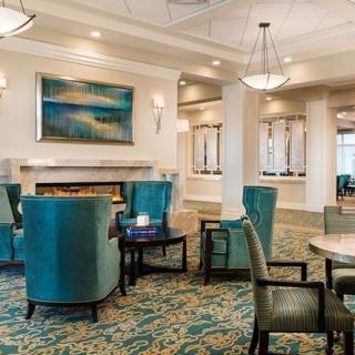A modern lounge area with teal chairs, a carpeted floor, and contemporary artwork.