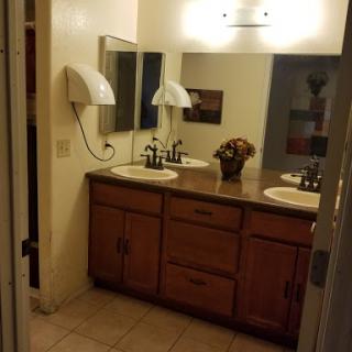 A spacious bathroom featuring a double vanity with wooden cabinets and decorative elements.