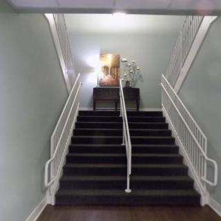 A staircase with a decorative table at the top, featuring a painting and a plant.