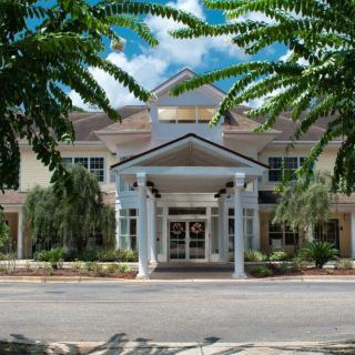 A view of a building with a prominent entrance surrounded by trees under a blue sky.