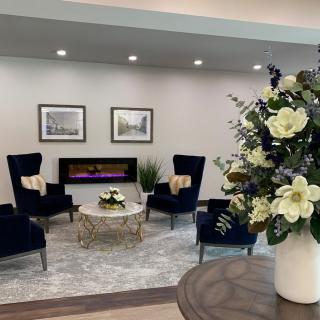 A modern lobby with comfortable seating, a decorative fireplace, and a floral arrangement.