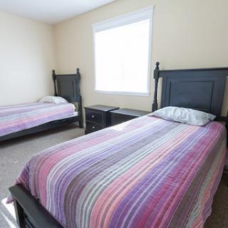 A simple and cozy bedroom featuring two twin beds with striped bedding.