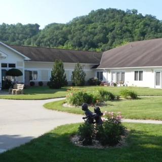 A serene image of a building surrounded by lush greenery, with a pathway leading through a well-maintained garden.