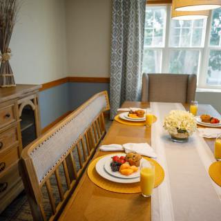 A cozy dining room table set for breakfast with fruit and juice.
