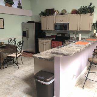 A modern kitchen with dining area featuring a refrigerator, stove, and countertop seating.
