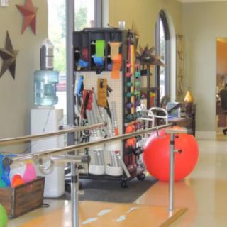 A physical therapy clinic with various exercise equipment and a fitness ball.