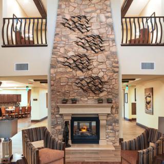A cozy living area featuring a tall stone fireplace and comfortable seating.