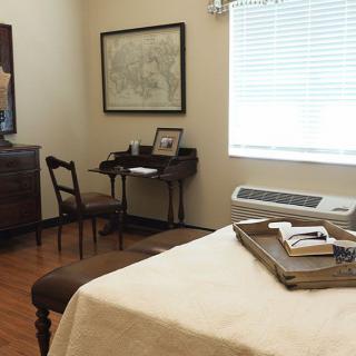A cozy bedroom featuring vintage furniture and a desk beside a window.