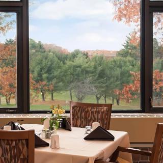 A cozy dining area with a scenic view of autumn trees through large windows.