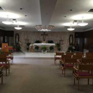 An interior view of a chapel featuring an altar and rows of seating.