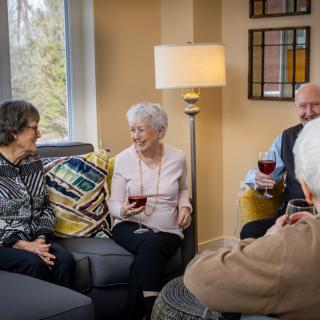 A group of seniors enjoying a conversation and drinks in a cozy living room setting.
