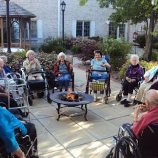 A heartwarming outdoor gathering of seniors around a fire pit, enjoying each other's company.