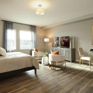 A beautifully designed modern bedroom featuring a cozy bed, stylish seating area, and ample natural light.