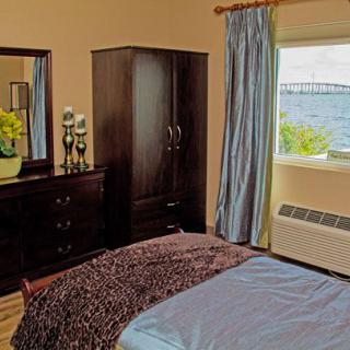 A cozy bedroom with dark wood furniture and a scenic coastal view from the window.