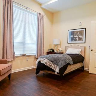 A cozy bedroom with a single bed, wooden floors, and soft lighting.