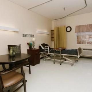 A clean and organized hospital room with a bed and seating area.