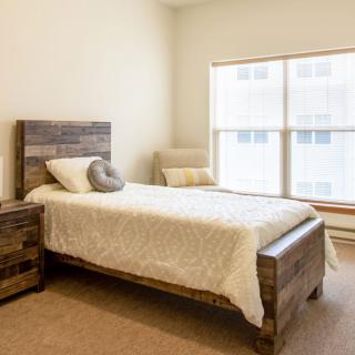A minimalist bedroom with a single wooden bed and large window.