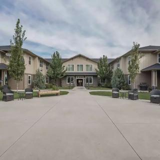 A wide driveway leads to the entrance of a large building with manicured landscaping and trees.