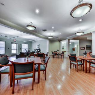 A spacious dining area with multiple tables and chairs, featuring hardwood flooring and contemporary lighting fixtures.
