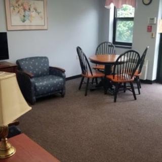 A cozy living room with a dining table and chairs next to an armchair.