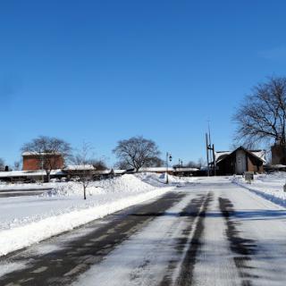 A serene winter scene featuring a snow-covered road under a clear blue sky.