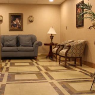 A cozy lobby area featuring a blue sofa, patterned armchairs, and decorative wall art.