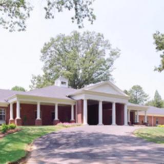 A suburban house with a large driveway and classical architectural columns.