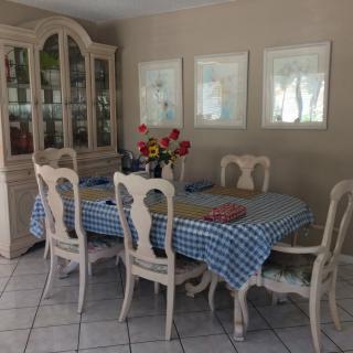 A cozy dining room with a checkered tablecloth, surrounded by elegant chairs and a china cabinet.