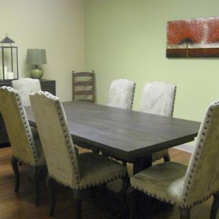 A modern dining room featuring a dark wooden table surrounded by elegant chairs, complemented by green walls and decorative artwork.