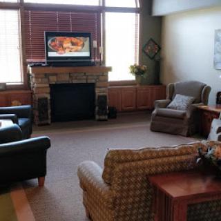 A cozy living room featuring comfortable seating and a television above the fireplace.