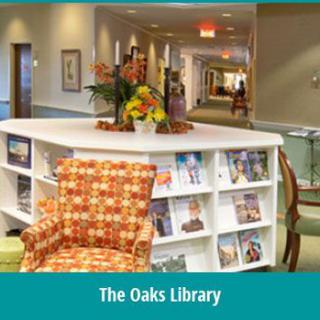 A cozy library corner with a bookshelf, patterned chair, and floral arrangement in The Oaks Library.