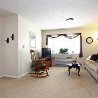 A cozy living room with a rocking chair, sofa, and television, featuring indoor plants and soft lighting.