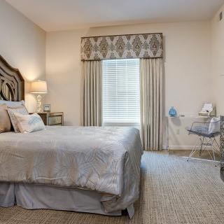 A well-decorated bedroom with a bed, lamp, and window with curtains.