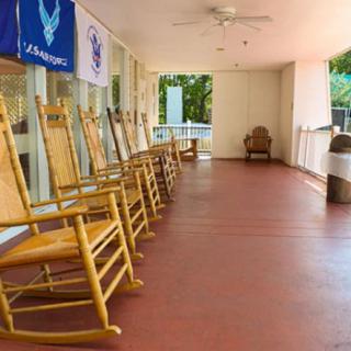 A peaceful covered porch with a row of wooden rocking chairs.