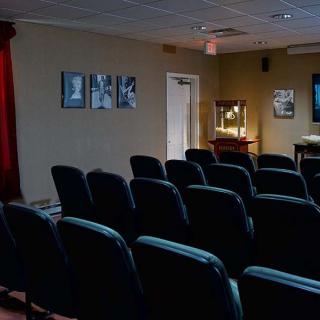 An empty movie theater with rows of seats and a projector.