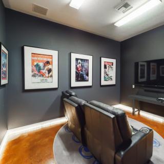 A cozy home theater setup with leather seating and movie posters on the walls.