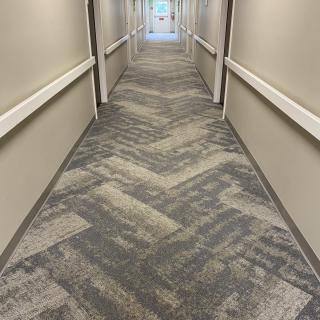 A long, carpeted hallway with patterned flooring and neutral-colored walls.