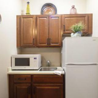 Compact kitchen area with a microwave, refrigerator, and cabinets.