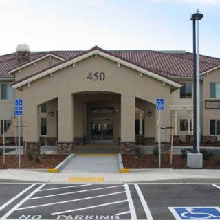 The image shows the front entrance of a building with a tiled roof, featuring accessible parking spaces in the foreground.